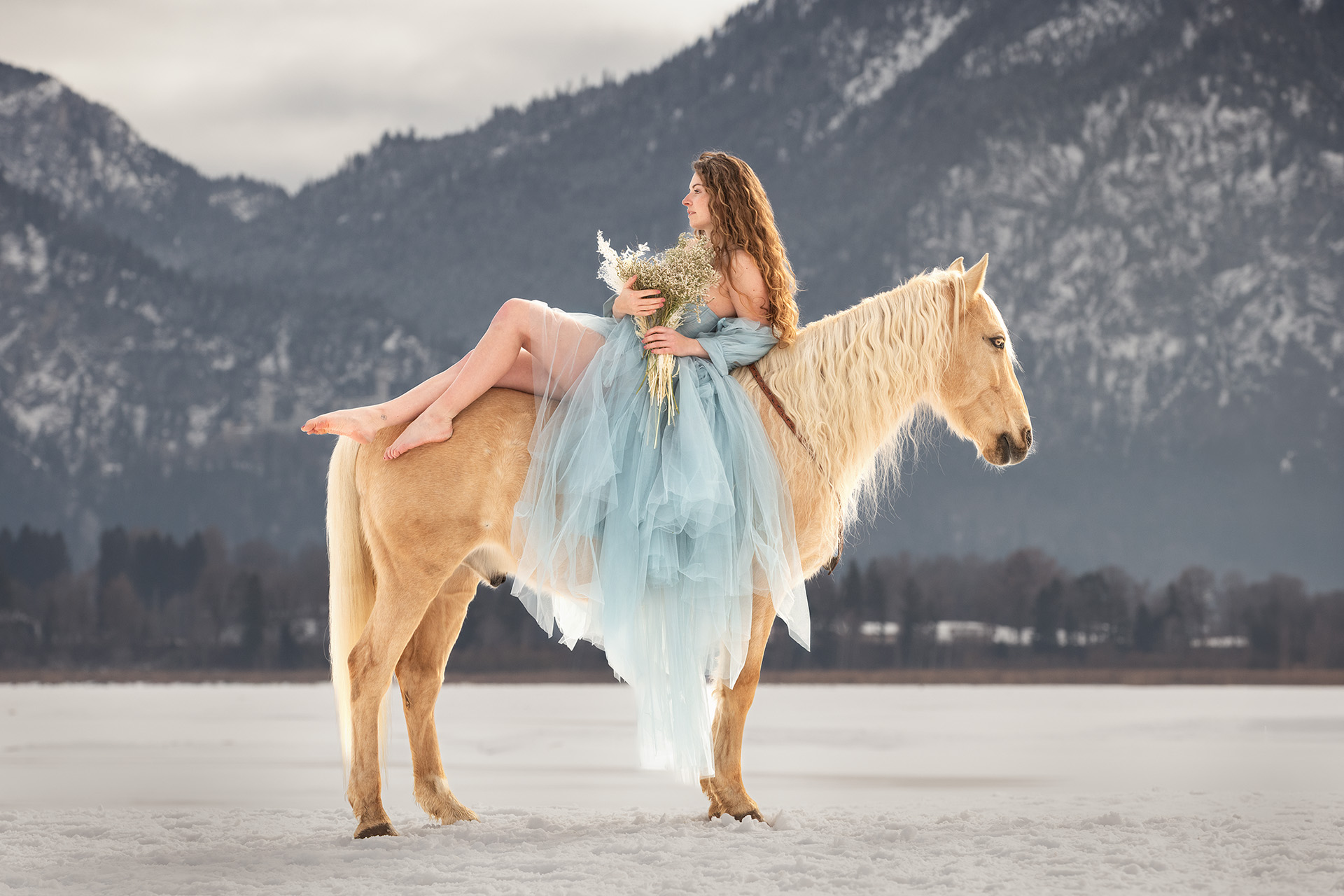 Besitzerin sitzt rückwärts auf einem Lusitano vor Bergkulisse